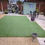 Artificial grass lawn surrounded by gravel and paving